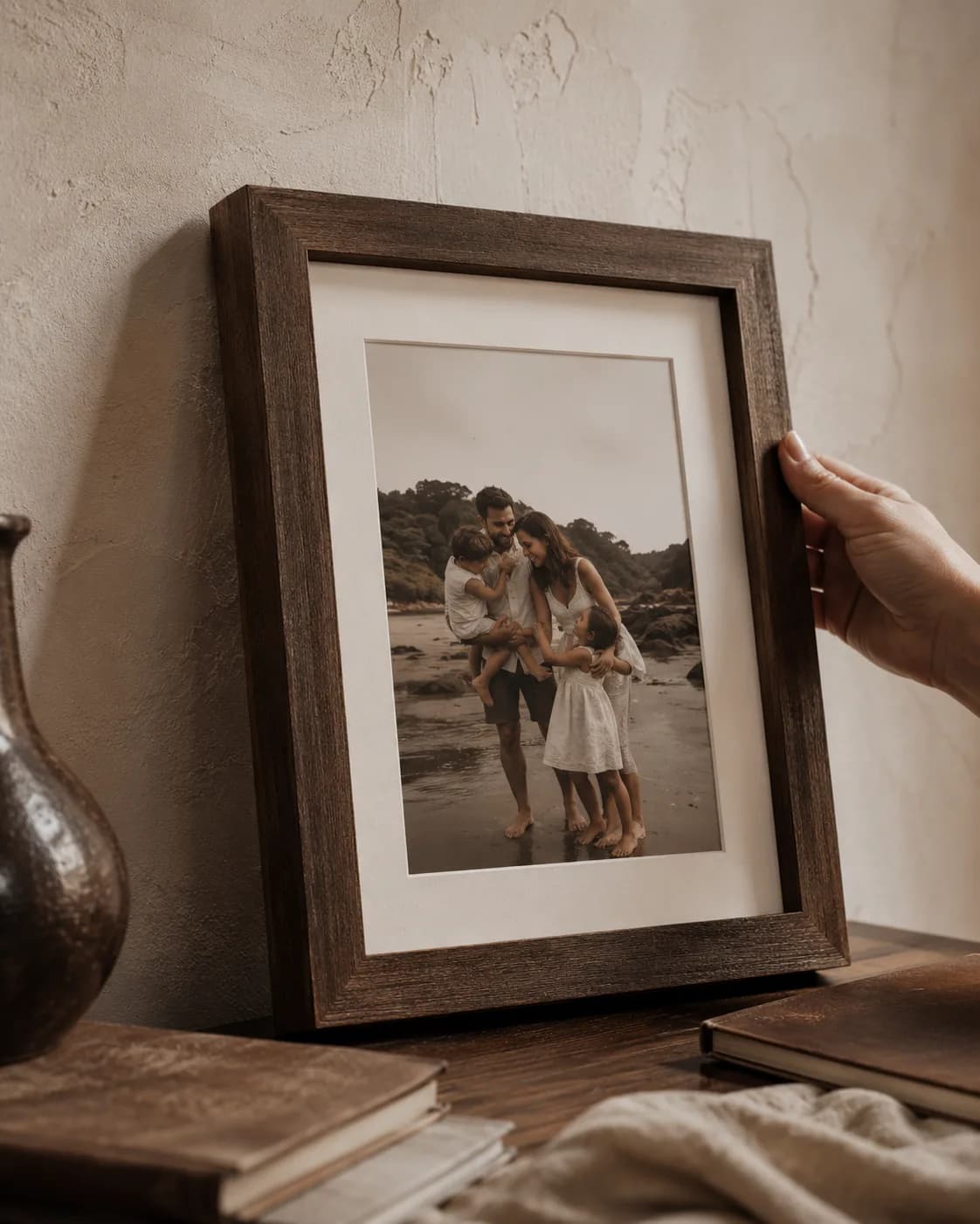 Quadro de família com moldura de madeira apoiado em uma mesa de madeira.
